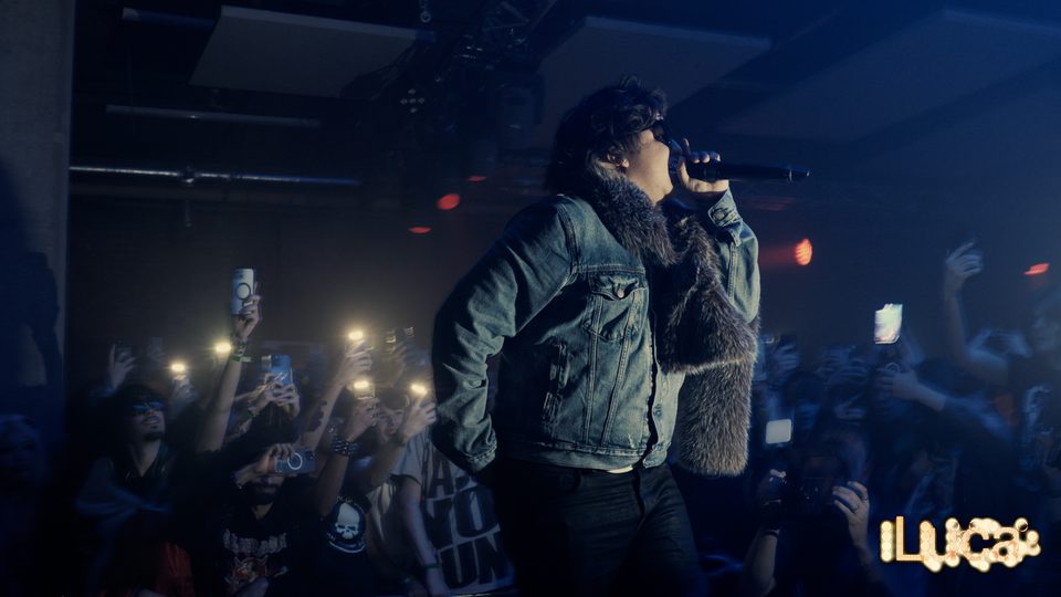 2Slimey on the mic in blue stage light above a crowd, shot by Luca Barbieri (lucabrbi)