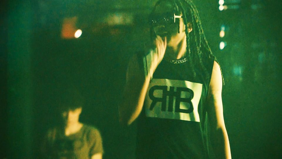 Che in sunglasses under green stage light